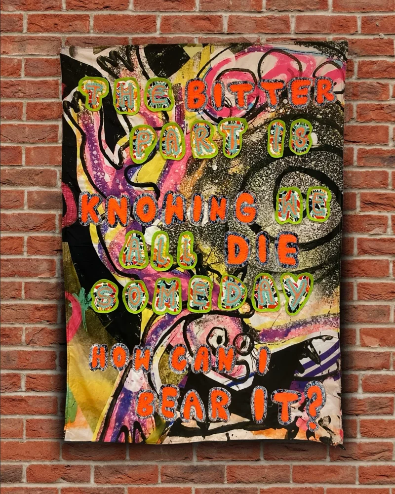 Kim's artwork titled 'Love - A Haiku which says 'The bitter part is, knowing we all die someday, how can i bear it?' overlayed on a brick wall background